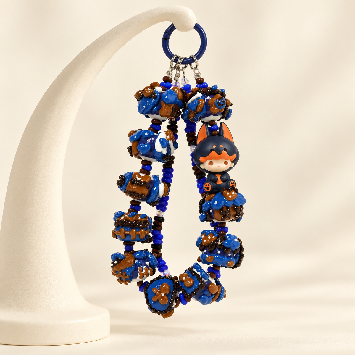 DIMOO Pajama Doorbell Man phone charm with blue and brown chunky beads on a cream studio background