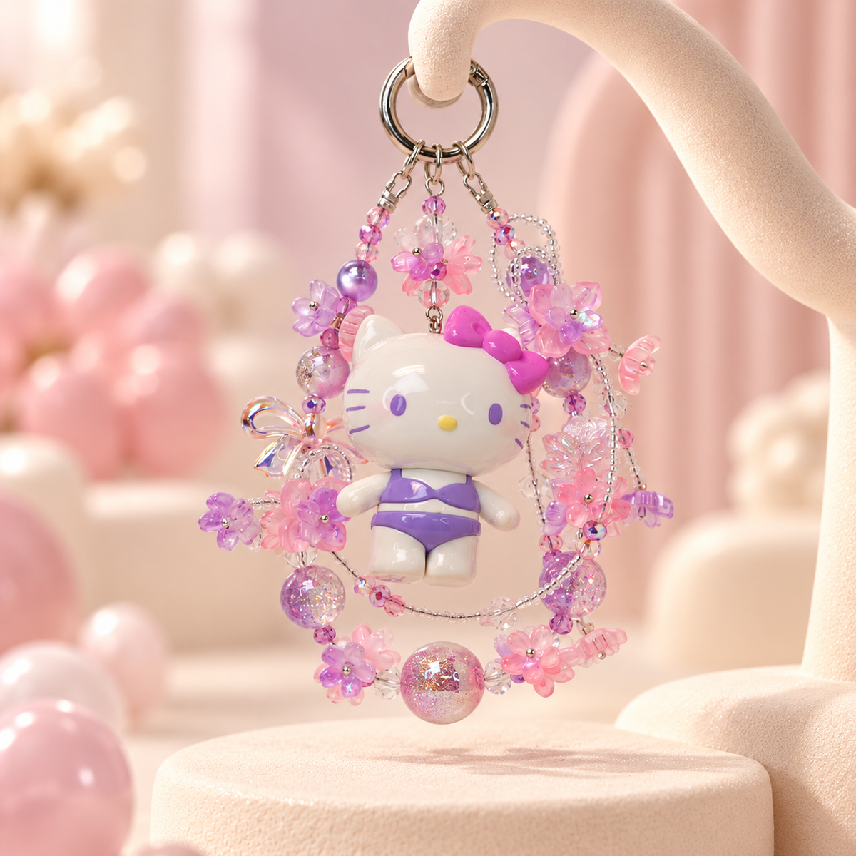 TOP TOY Hello Kitty Swimming Suit Party purple and pink glitter bead phone charm on a cream studio stand